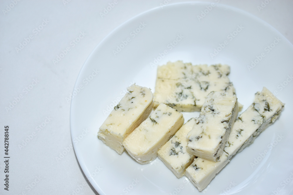 White cheese with blue mold on a white plate
