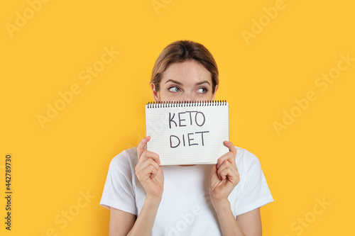 Woman holding notebook with phrase Keto Diet on yellow background