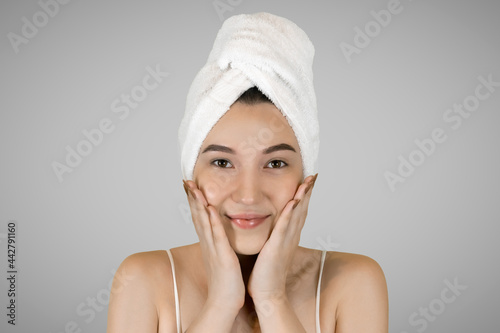 Washing your face. Closeup of woman cleaning skin with towel portrait. The woman touches her skin with her hands and smiles. High quality studio shot. 