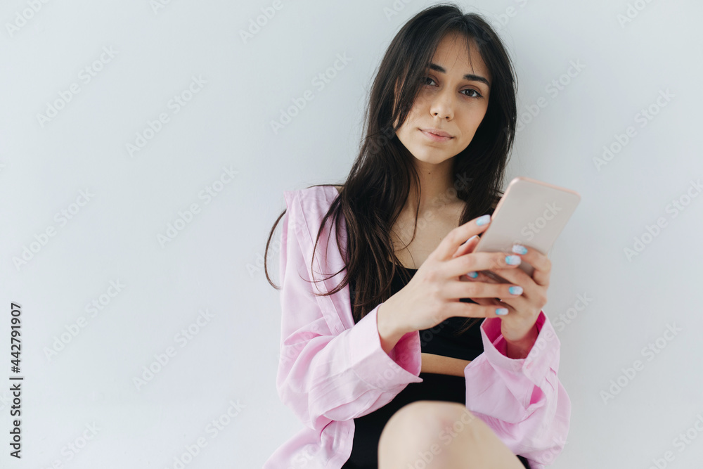 young armenian woman with smartphone looking at camera on white background young armenian woman with smartphone looking at camera on white background