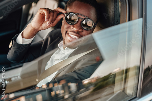 Joyful african american businessman inside of car