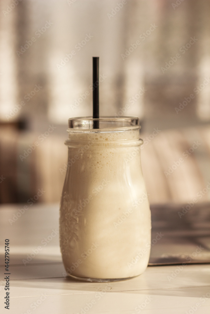 Milk shake, smoothie, in the glass mud or bottle with a straw on white wooden table in the light background. Tasty refreshment in a restaurant or cafe Milk shake, smoothie, in the glass mud or bottle with a straw on white wooden table in the light background. Tasty refreshment in a restaurant or cafe