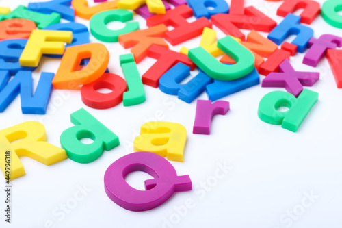Many colorful magnetic letters on white background, closeup