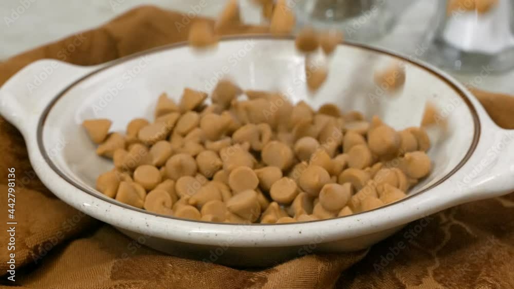 Pouring butterscotch morsels into a a dish super slow motion Pouring butterscotch morsels into a a dish super slow motion