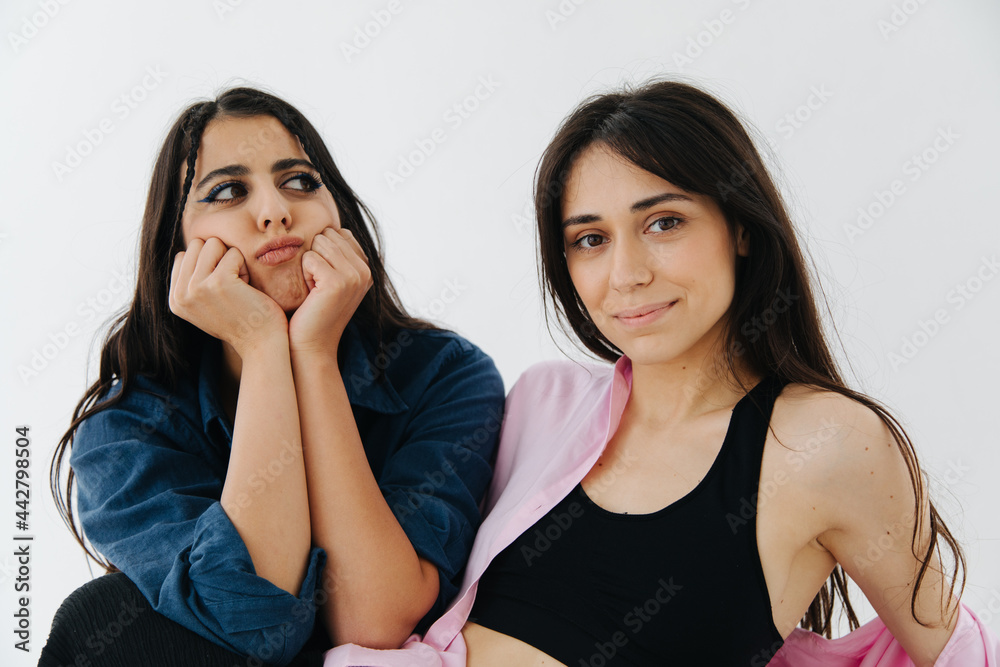 happy armenian woman looking at camera near displeased friend isolated on white happy armenian woman looking at camera near displeased friend isolated on white