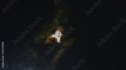 A girl sunbathes on a stone island in the middle of a lake in Karelia, Russia. photo