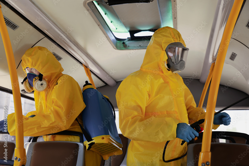 Public transport sanitation. Workers in protective suits disinfecting bus salon Public transport sanitation. Workers in protective suits disinfecting bus salon