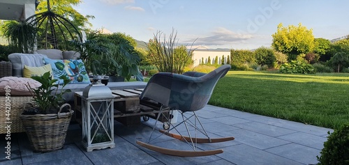 Meble tarasowe w ogrodzie i nowoczesny fotel na biegunach na tarasie photo