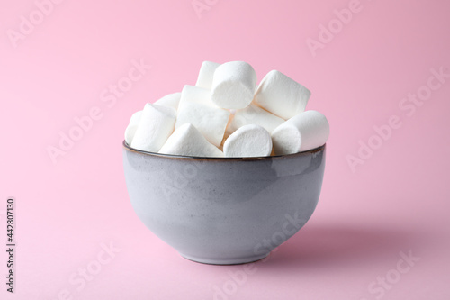 Delicious puffy marshmallows in bowl on pink background