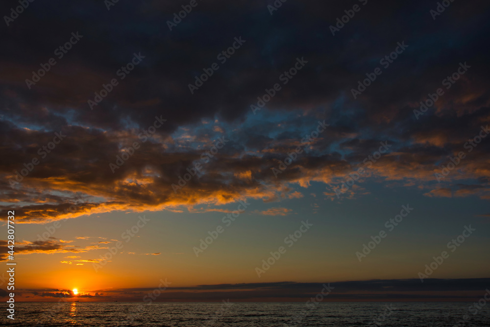 A sea sunset during the white nights with a colorful and picturesque cloudy sky, a light breeze on the gloomy dark sea.