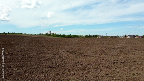 Photos Aerial drone view flight over huge plowed field and blue sky.