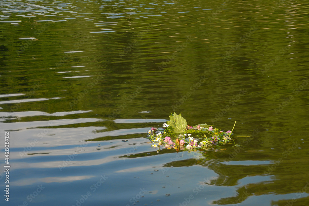 Fototapeta premium A wreath of wildflowers is floating on the water. Ukrainian holiday of Ivan Kupala in summer.