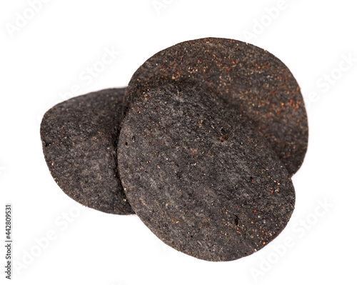 Black potato chips isolated on white background. Black chips with activated charcoal and red pepper. © vandycandy