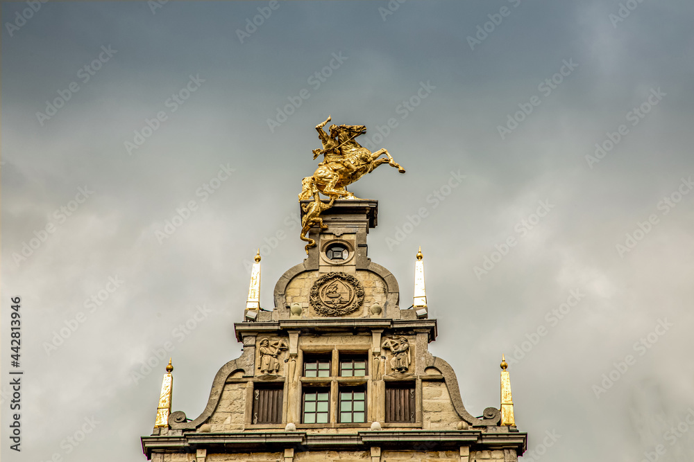 roofs of ancient buildings with gilded figures against a gray sky in antwerp on the central square