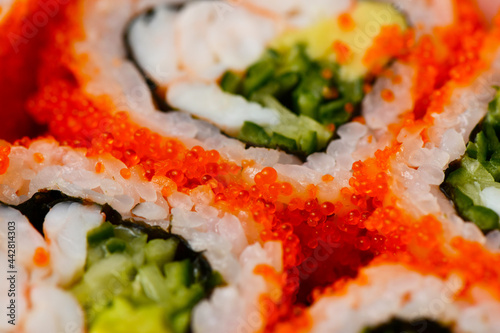Delicious California sushi roll. Flying fish caviar on chopsticks. Asian food, Japanese makizushi, delivery concept. Tasty and colorful closeup image of seafood restaurant menu.