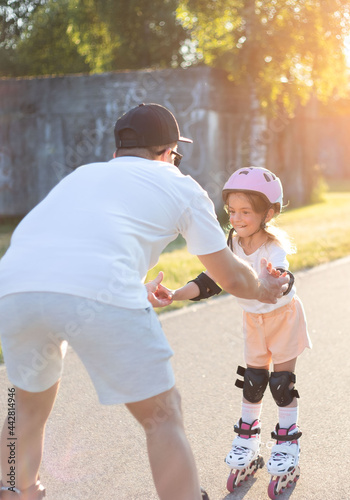 Naklejka Father teaching the daughter skating on rollers.