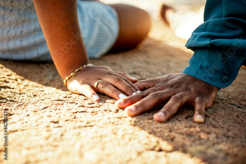 Mãos de um casal sentado sobre as pedras