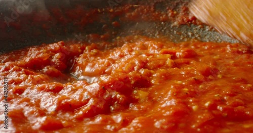 Tomato sauce boiling in a pan, being stirred with a spoon. Hot tomato sauce cooked for pizza or pasta. Italian cuisine, food and drink 4k footage photo