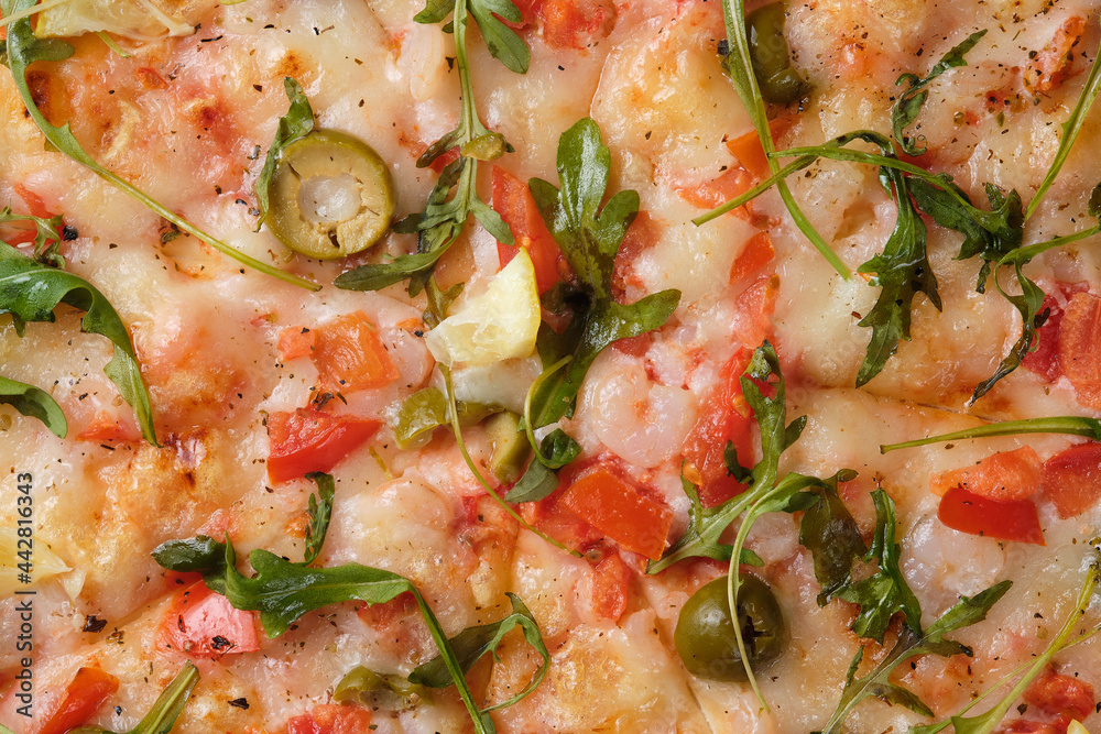 Pizza with tomatoes, shrimps, arugula, olives, lemon, mozzarella cheese, spices and tomato sauce. A closeup of a pizza. Pizza with tomatoes, shrimps, arugula, olives, lemon, mozzarella cheese, spices and tomato sauce. A closeup of a pizza.