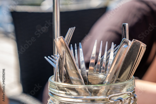 Close up on forks and knifes in a glass bottle