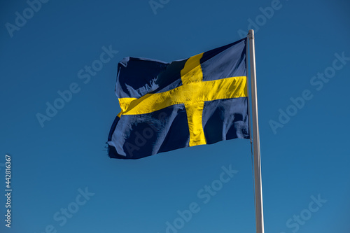 The Swedish flag blowing in the wind with a blue sky