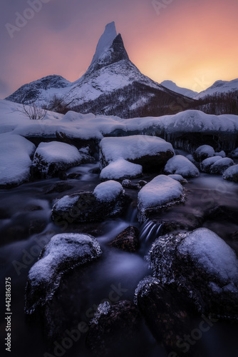 Beautiful ice crystals of the frozen river and waterfall in the snowy winter landscape near Stetinden. Stetinden is an impressive mountain in northern Norway, photo was taken at sunrise 