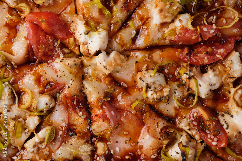 Pizza with tomato, chicken, ham, onion, sesame, mozzarella cheese, spices, tomato sauce and teriyaki sauce. A closeup of a pizza. Pizza with tomato, chicken, ham, onion, sesame, mozzarella cheese, spices, tomato sauce and teriyaki sauce. A closeup of a pizza.