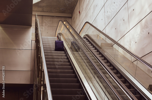 Suitcase moving up escalator. Arriving to a new place, travelling concept, touristic background