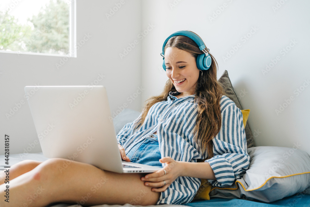 cheerful girl with headphones looking at her laptop cheerful girl with headphones looking at her laptop