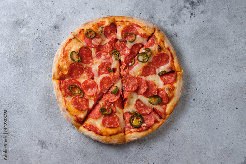 Pepperoni pizza with jalapeno peppers. A closeup of a pizza. Flat lay. On a light background