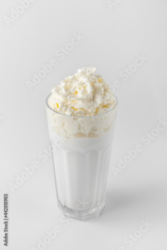 glass with white milkshake and cream on a gray background with natural shadows