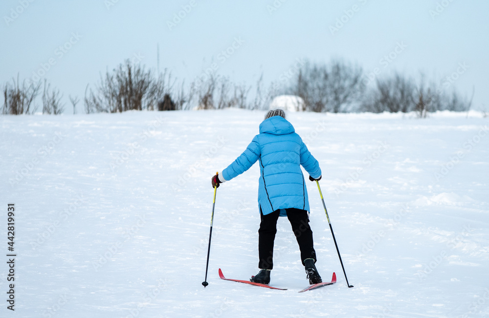 A woman in a blue jacket skiing up a snowy slope.