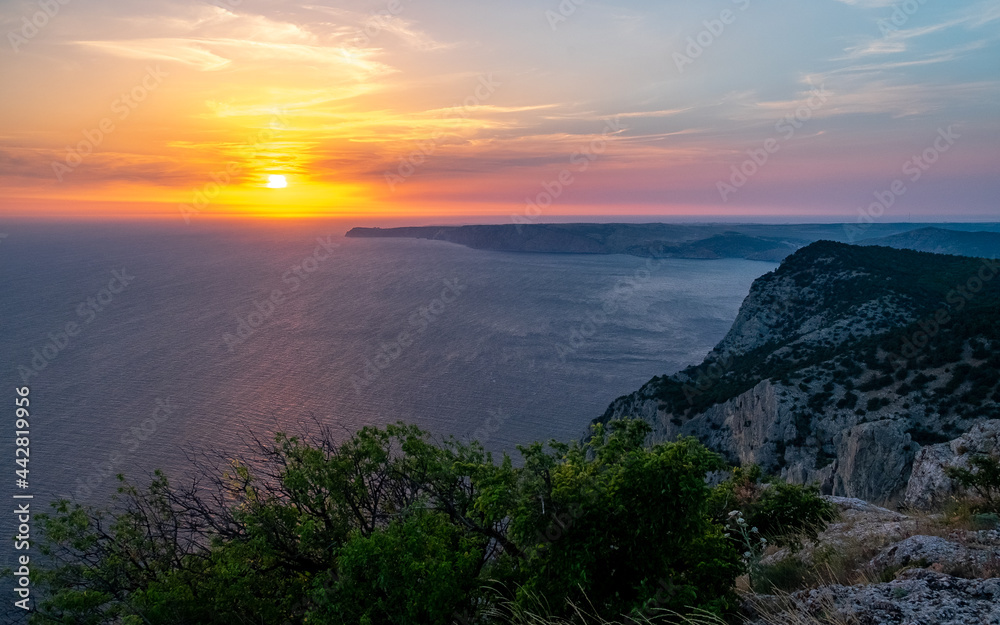 The sun setting into the sea and the long cape crashing into the Black Sea at sunset. Coast of the Crimean Peninsula near Balaklava.