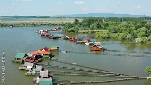 Aerial view of the famous Bokod Floating Village with piers and traditional wooden fishing cottages built on the lake Bokodi. Walkboards leading to small fishing houses floating on water in Oroszlány