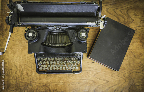 antique black typewriter on a mahogany wood desk viewed from above