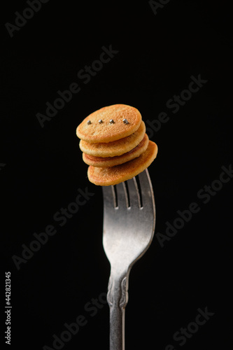 Mini pancakes on a fork on a dark background
