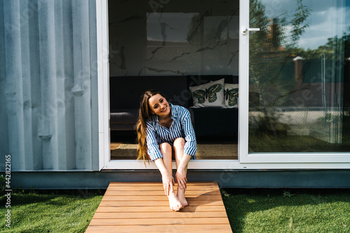 carefree beautiful female sitting in front of modern tiny house