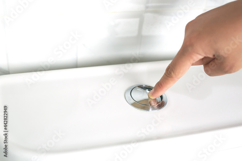 A man's hand pressing a button in the toilet