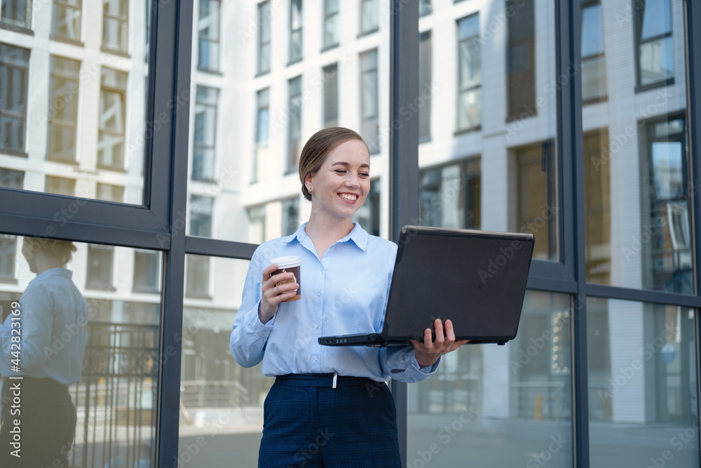 Portrait of happy business young woman, smiling while drink coffee and work with laptop Portrait of happy business young woman, smiling while drink coffee and work with laptop