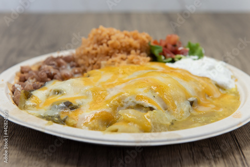 Melted cheese covrers these green enchiladas served with a scoop of Mexican rice and beans for lunch