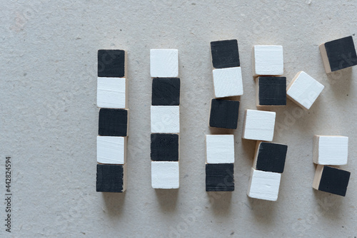 black and white hand painted wood craft cubes arranged on a millboard background - photographed from above in a flat lay style