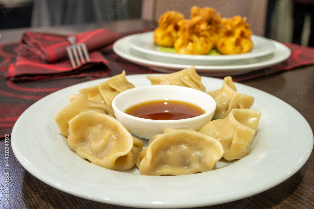 Serving of steamed gyozas garnished with soy sauce on a white plate in a Chinese restaurant Serving of steamed gyozas garnished with soy sauce on a white plate in a Chinese restaurant