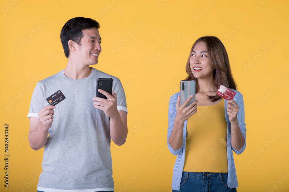 Excited Asian couple holding credit card and smartphone feeling excited isolated on colour background Excited Asian couple holding credit card and smartphone feeling excited isolated on colour background