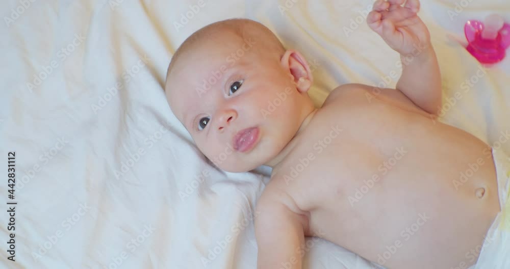 Portrait of a cute baby who lies on a bed sheet with a surprised look.view from above. Portrait of a cute baby who lies on a bed sheet with a surprised look.view from above.