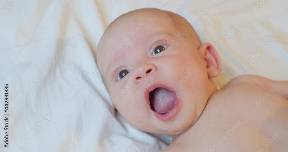 Portrait of a cute baby who lies on a sheet with a surprised look. Portrait of a cute baby who lies on a sheet with a surprised look.