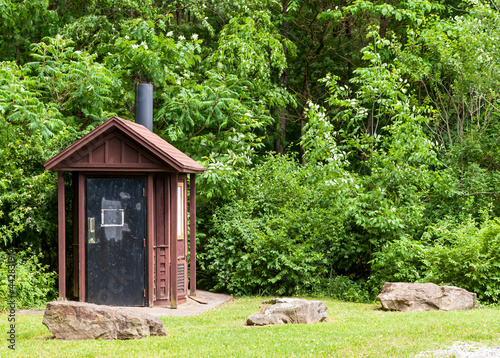 An outhouse in the woods in Warren County, Pennsylvania, USA on a sunny summer day photo