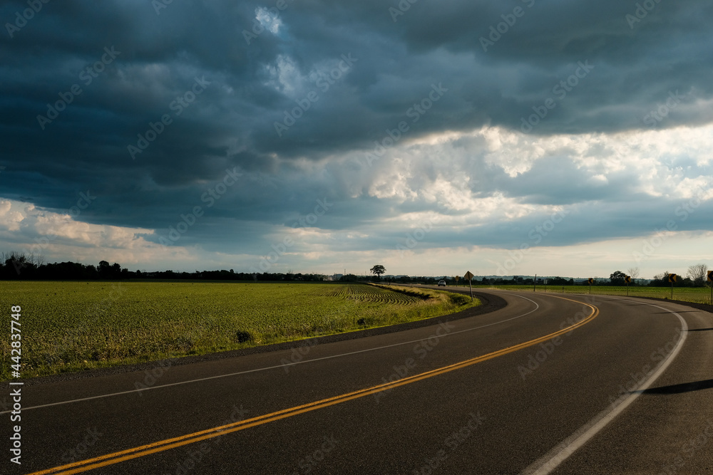 Curved road with dramatic summer storm clouds