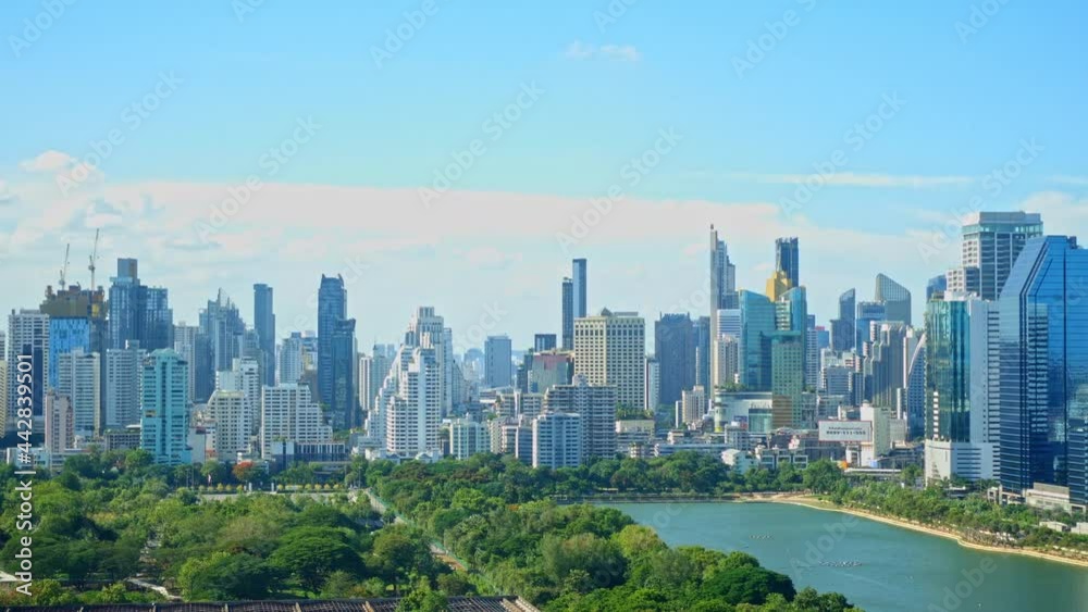 Stationary time-lapse of downtown Bangkok city skyline, cityscape, and the skyscrapers of the business district, Benjakitti Park, CTI Tower. Wide panoramic distant view daytime cloudy sky