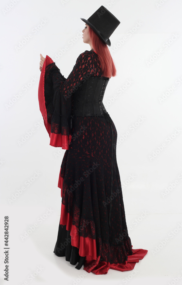 full length portrait of red haired woman wearing long black gothic vampire gown. standing pose on white studio background full length portrait of red haired woman wearing long black gothic vampire gown. standing pose on white studio background