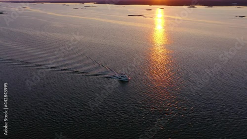 Aerial view around a yacht cruising in tranquil, mirroring sunset ocean - circling, drone shot photo